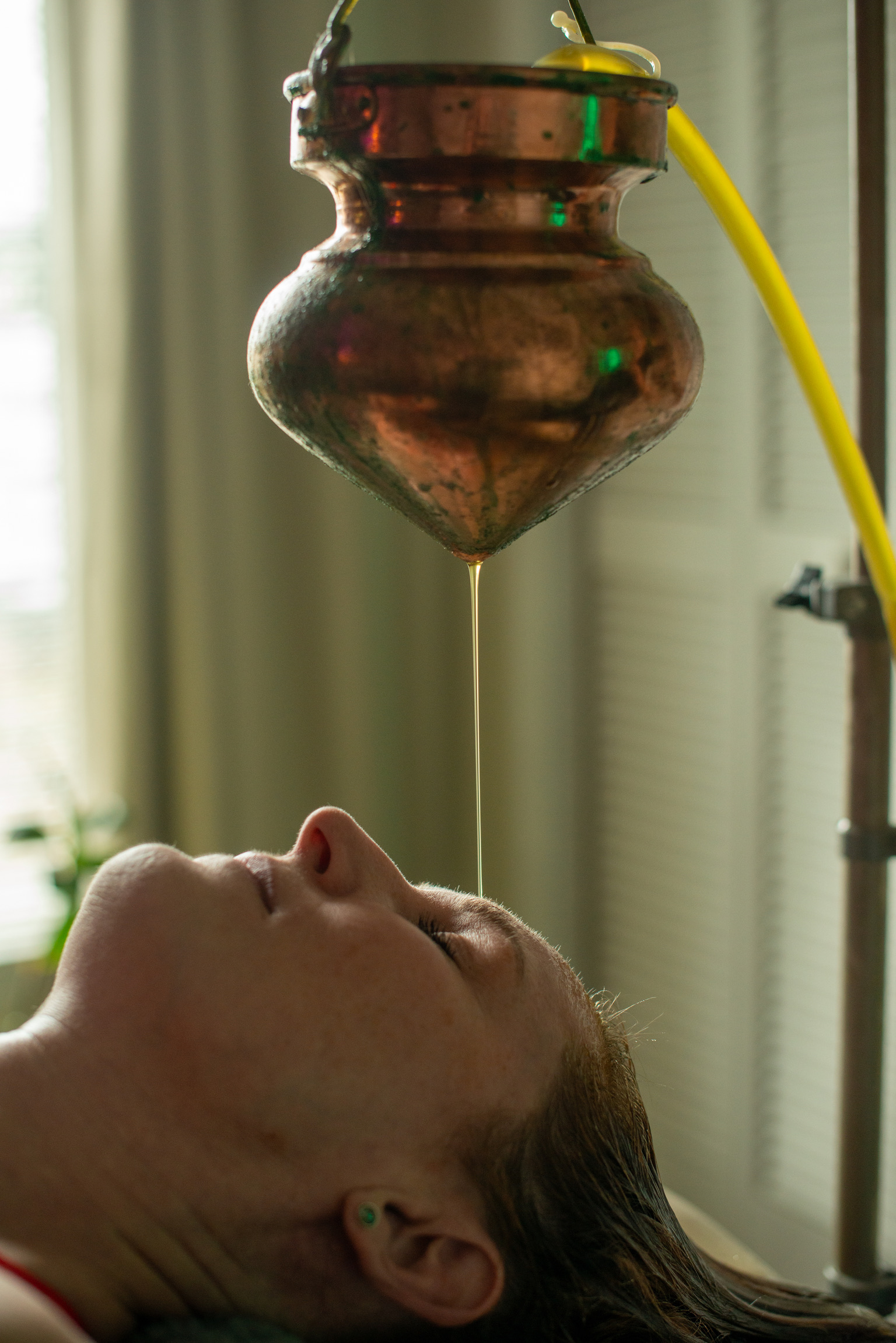 Shirodhara treatment at Bodhi Salt — warm herbal oil poured from copper vessel onto forehead