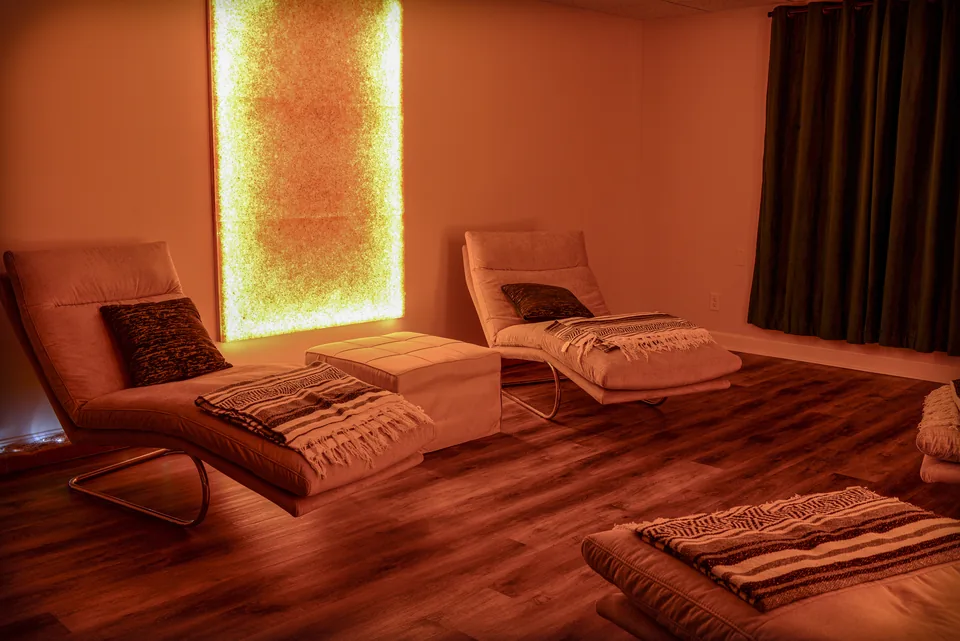 Himalayan salt room with glowing salt wall and lounge chairs at Bodhi Salt Center